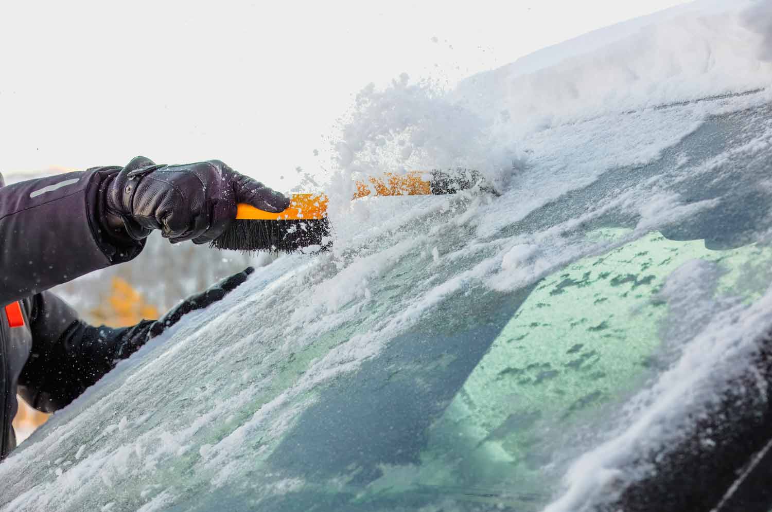 using a scraper to remove ice from a car windshield